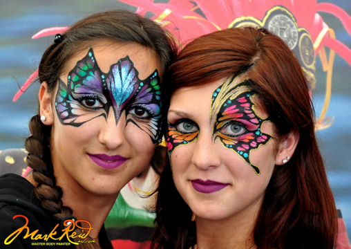 two ladies in colorful masks around their eyes that have a butterfly feel